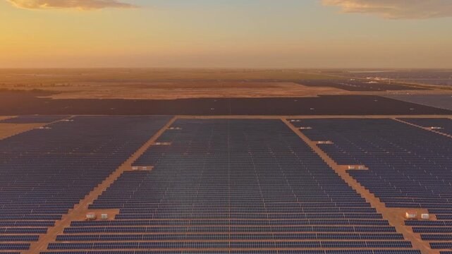 Solar photovoltaic panels at sunrise/sunset; wind turbine power plant; new energy