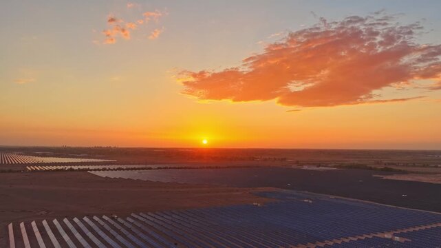 Solar photovoltaic panels at sunrise/sunset; wind turbine power plant; new energy