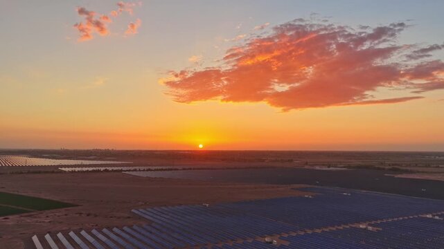 Solar photovoltaic panels at sunrise/sunset; wind turbine power plant; new energy