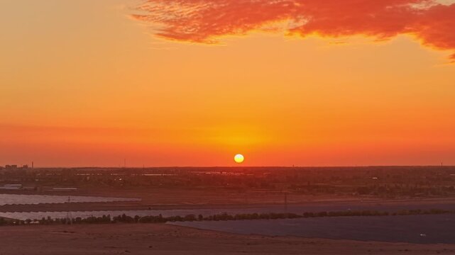 Solar photovoltaic panels at sunrise/sunset; wind turbine power plant; new energy