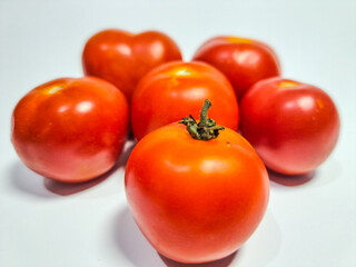 Fresh red tomatoes gleam against a clean white backdrop © Muhammad Idhwar