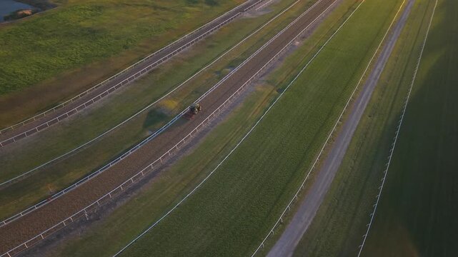 Newcastle Racecourse tracks and green turf and race path milled with tractor, warm sunset light, aerial backdrop