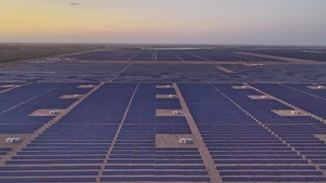 Solar photovoltaic panels at sunrise/sunset; wind turbine power plant; new energy