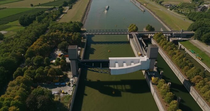 Aerial view of a large Dutch sluice complex and bridge with barges passing along the river, surrounded by a vast flat polder landscape and waterways.
