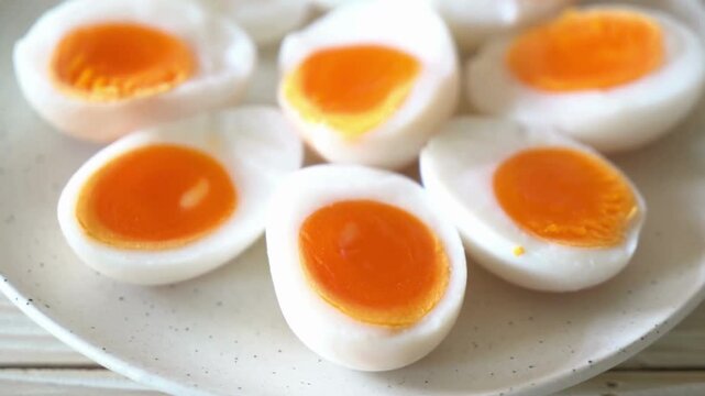 Soft boiled eggs with orange runny yolk, halved medium boiled chicken eggs on white plate, healthy protein breakfast food