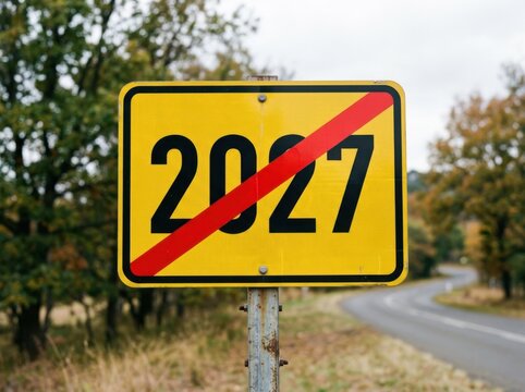 Yellow road sign with the year 2027 crossed out by a red diagonal line, indicating the end of a period or deadline