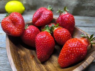 Ripe sweet strawberries in a wooden plate on a wooden © nicolas