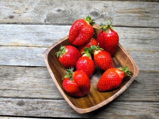 Ripe sweet strawberries in a wooden plate on a wooden © nicolas