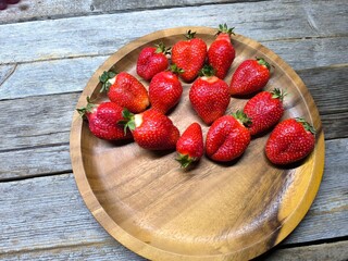 Ripe sweet strawberries in a wooden plate on a wooden © nicolas