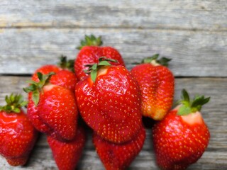 Collection of ripe red strawberries scattered on wooden table in rustic style. © nicolas
