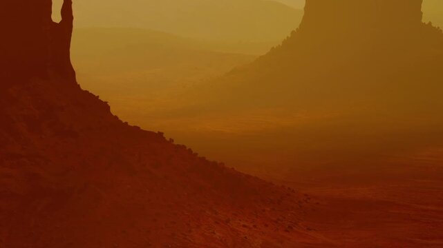 A desert landscape at sunset. The sky has warm colors and rock formations stand prominently in the foreground while distant mountains are visible.
