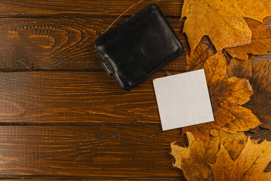 Leaves and blank card on wooden table in autumn setting