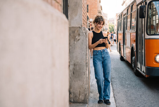 Young woman using smartphone on urban street corner