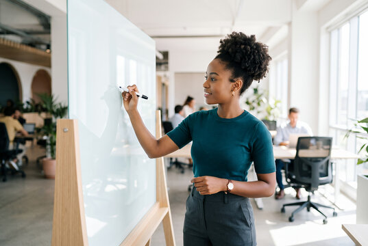 Young woman writing on whiteboard in modern office space