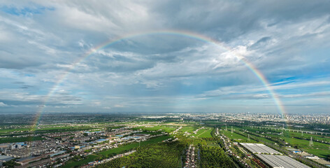 Naklejka premium Full Rainbow Over Urban and Rural Landscape
