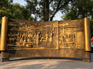 Bronze relief mural of ancient Chinese street life scene © NgoVan
