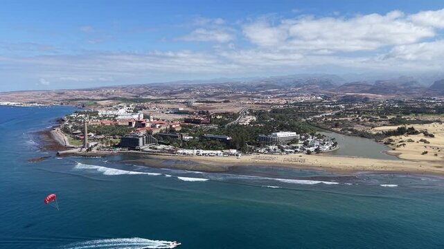 Aerial Dolly Out at Maspalomas Beach revealing Parasailing at Sea