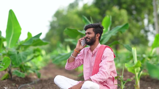 indian farmer sitting at banana agriculture field and talking on mobile phone