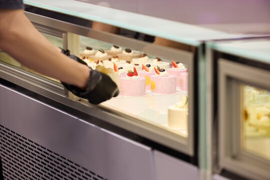 Bakery worker selecting cakes in a display case