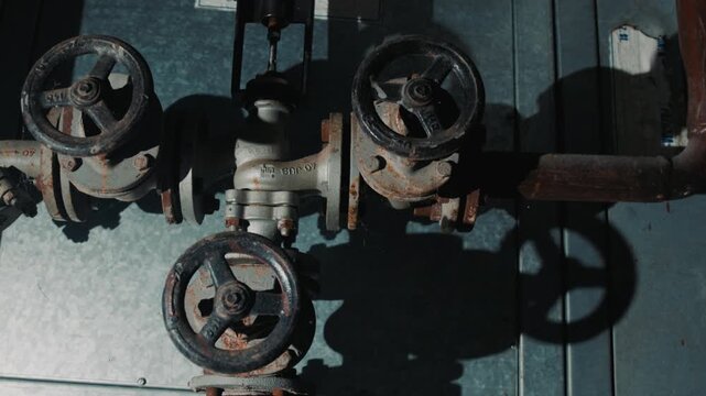 Old rusted steam system of valves and pipes in an abandoned factory.