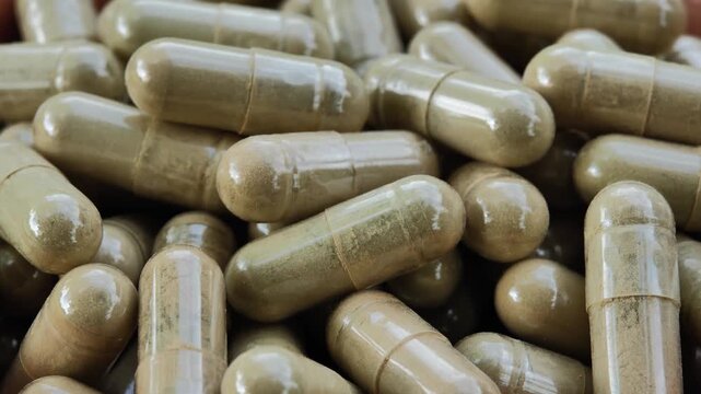 Close-up of capsules containing dried moringa leaf powder, representing herbal supplements, natural plant ingredients, and botanical products. The image highlights the capsules and green moringa mater