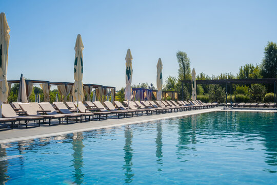 Row of lounge chairs and umbrellas beside a swimming pool on a clear day