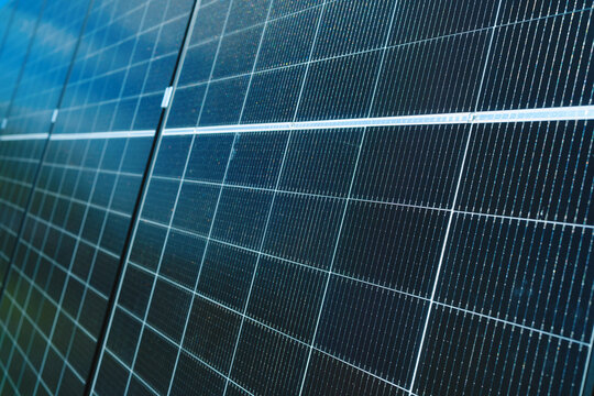 Solar panels reflecting blue sky and white clouds on an outdoor background