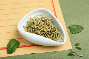Dried honeysuckle buds in white bowl with mint leaves © PhamThi