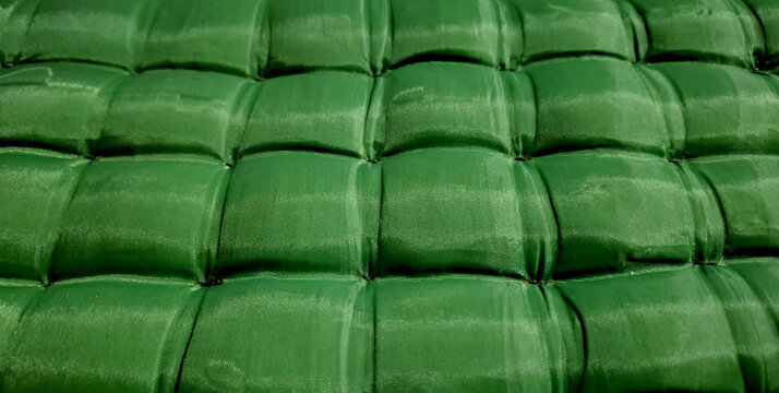 Angled view showing the soft tufted square padding texture of a green inflatable mattress. Perfect for camping gear, comfort, and interior design backgrounds.