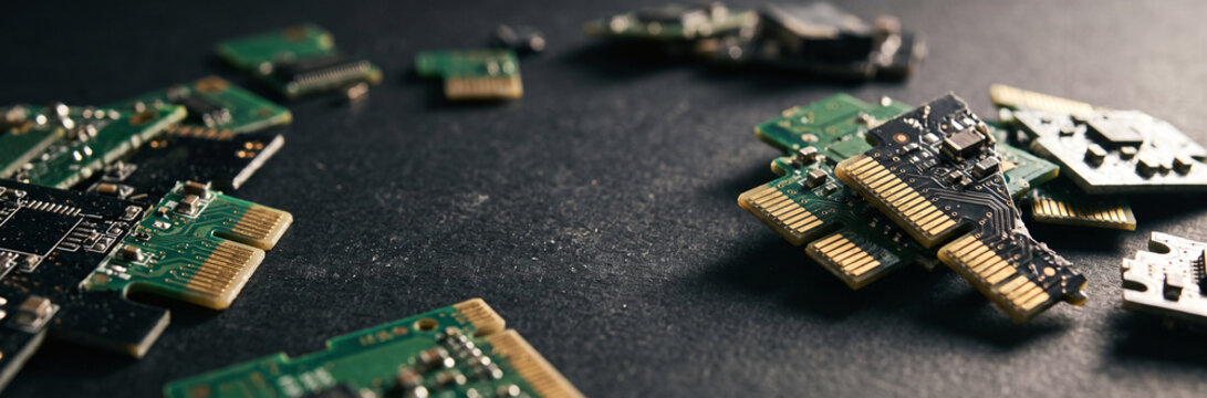 Small broken green circuit board fragments on a dark background