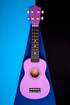 Four-string ukulele guitar on a colored background