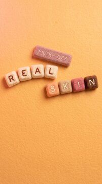 Felt Blocks Spelling Real Skin Filter Off on Peach Background