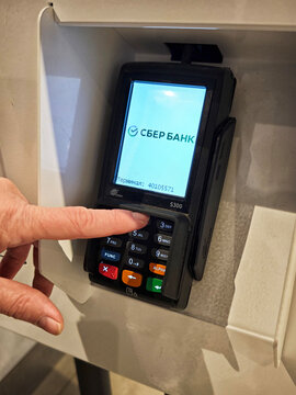Kirov, Russia - April 06, 2026: Customer uses a card reader at a Sberbank payment terminal in a busy shop