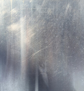 Scratched metallic texture background with subtle light reflection and worn surface