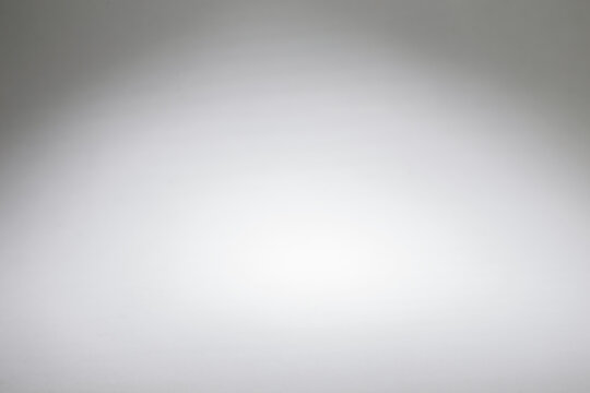 Abstract white gradient background with center spotlight highlight and soft vignette effect