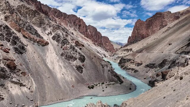 Zanskar, India : Beautiful footage of tsarap river flows in the valley heading to Phuktal gompa of Ladakh, India with dirt mountain road on the remote Zanskar valley on sunny day in the Himalayas