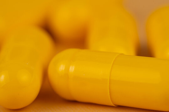 Extreme macro abstract view of a shiny yellow medicine capsule with soft bokeh