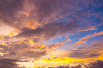 Fototapeta premium Stunning vibrant sunset sky with colorful clouds and twilight glow,A breathtaking view of a vibrant sunset sky filled with dramatic colorful clouds, glowing golden light, and soft purple twilight hues