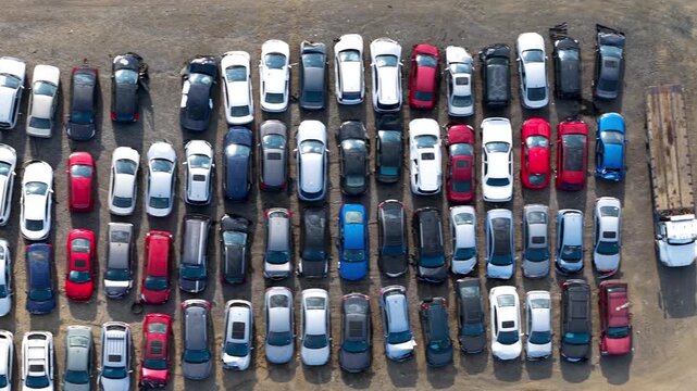 Top down aerial view of a tow truck in a salvage yard full of damaged cars