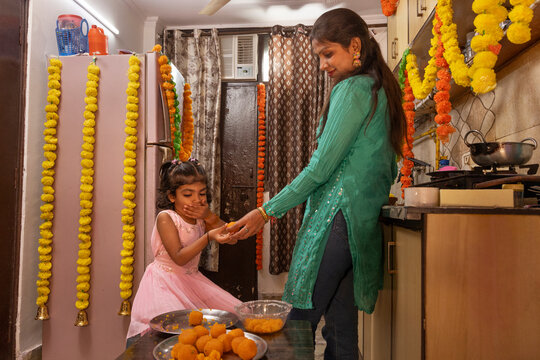Mother giving sweets to daughter in a decorated kitchen