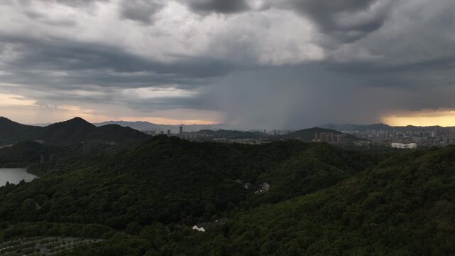 City skyline and storm clouds over green mountains