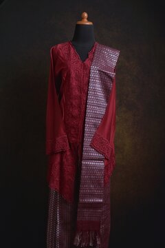 Maroon embroidered kebaya with songket skirt and shawl displayed on a dress form