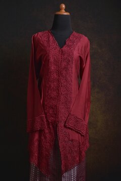 Maroon embroidered kebaya with songket skirt and shawl displayed on a dress form