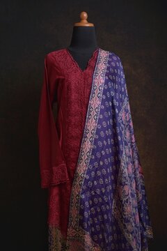 Maroon embroidered kebaya with batik skirt and shawl displayed on a dress form
