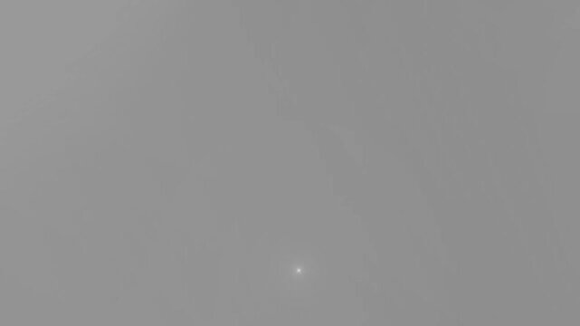 Lens flare light shines subtly at the bottom center of a smooth grey neutral backdrop with clear copy space.