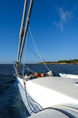 Bow of a sailing trimaran yacht with dinghy and coconuts © Irina