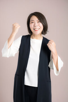 仕事の成功を喜びガッツポーズする働く40代女性、チャレンジ、挑戦や応援とやる気を表現するビジネスポートレートカメラ目線の笑顔