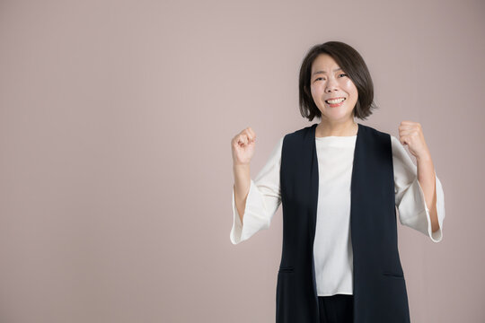仕事の成功を喜びガッツポーズする働く40代女性、チャレンジ、挑戦や応援とやる気を表現するビジネスポートレートカメラ目線の笑顔