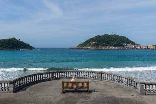 Frau auf einer Bank an der Promenade am Bicentennial Balcony, La Concha Strand, San Sebasti&aacute;n, Spanien