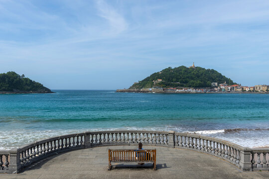 Frau auf einer Bank an der Promenade am Bicentennial Balcony, La Concha Strand, San Sebasti&aacute;n, Spanien